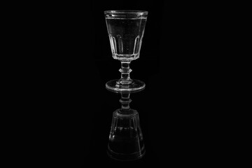 Closeup of a glass of water on a black background. Still life of an illuminated vintage glass on a black backdrop.
