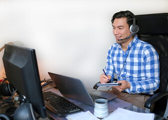 Man with headset in a video call - working from home with a laptop in the living room