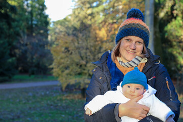 Portrait of a smiling mother with a baby boy son in the park in the winter 
