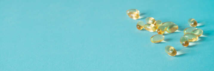 Pile of capsules Omega 3 on blue background. Close up, top view.
