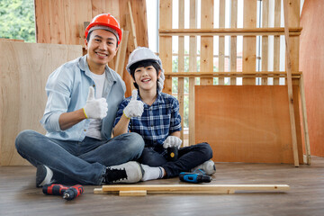 father and son in safety helmet sitting in carpentry workshop.