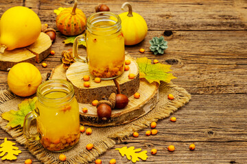 Vitaminic healthy sea buckthorn tea in small glass jars with fresh berries and autumn decor