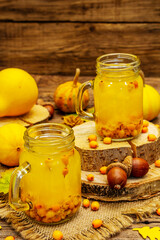 Vitaminic healthy sea buckthorn tea in small glass jars with fresh berries and autumn decor