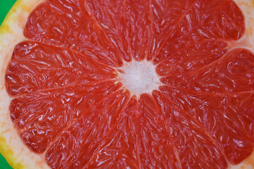 Ripe and tasty fruits, fresh grapefruit cut in half, sliced grapefruit set on a green fabric background.