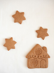Gingerbread cookies in the shape of a house and stars on a white background