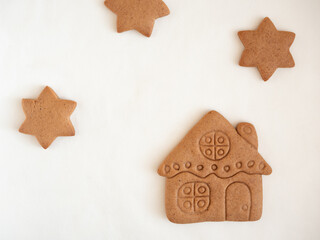 Gingerbread cookies in the shape of a house and stars on a white background