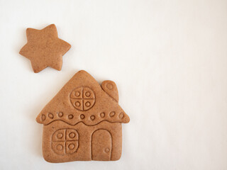 Gingerbread cookies in the shape of a house and stars on a white background
