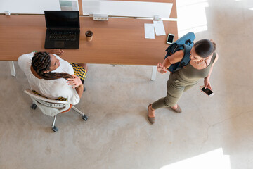 Aerial of Latin business woman saying good bye in coworking open space. .