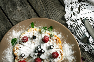Plate with Belgian waffle and berries, sprinkled with powdered sugar. Daylight. Top view