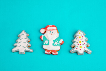 Christmas gingerbread colorful cookies in the shape of Christmas trees, Santa Claus on a turquoise background.