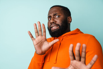 Naklejka premium Frightened african american man showing stop gesture at camera