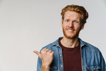 Confused unshaven redhead guy pointing finger aside