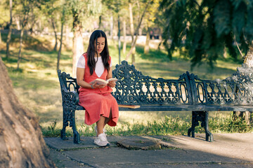 Chica leyendo en el parque, sentada en una banca,