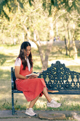 Chica leyendo en el parque, sentada en una banca del parque, al aire libre