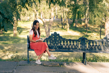 Chica leyendo en el parque, sentada en una banca del parque, al aire libre