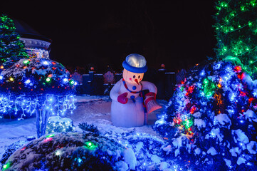 House Adorned with Christmas Holiday Lights and Decorations including Santa Snowman and Giant Trees Illuminated at Night.Christmas house