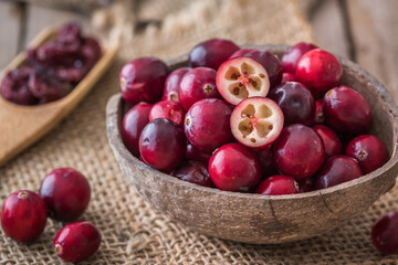 Raw cranberries in coconut shell on wooden table