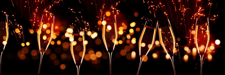 Celebrations with champagne in front of red glittering fireworks sky and golden bokeh. Horizontal background for silvester and wedding. Special occasion concept. - obrazy, fototapety, plakaty