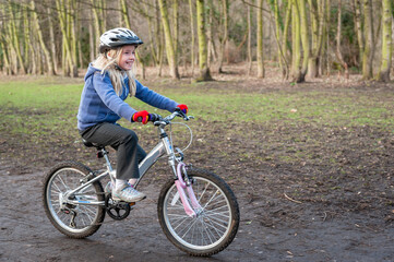 A happy young girl rides a bike along a country track