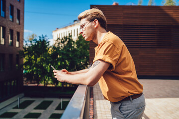 Pensive guy with mobile phone standing in city