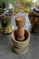 Wooden pestle and mortar with  with herbal jars on the background