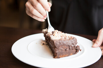Close-up of woman's hand cutting chocolate pastry