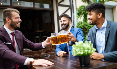 Cheerful old friends having fun and drinking beer at bar counter in pub.