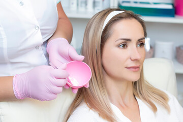 Fototapeta premium cosmetology. young woman with receiving facial cleansing procedure in beauty salon.