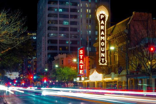 Austin, TX--Jan 9, 2019; time exposure of car lights streaking past the Paramount and State theaters, music venues, in downtown Texas state capital illuminated by neon marque signs at dusk