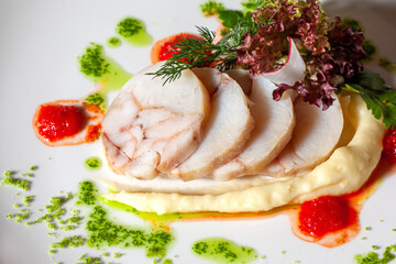 fish dish with potatoes and herbs on a white plate close up