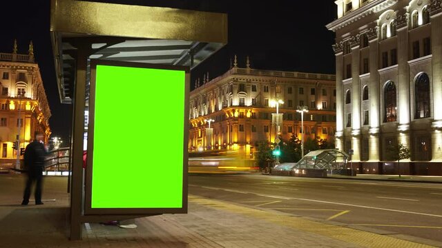 Billboard with a chroma key green screen on n bus stop at night. Time Lapse.
