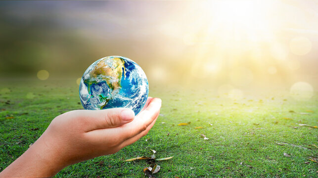 hand holding  Earth on green grass and sunny sky background. Elements of this image furnished by NASA