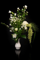 Pretty white flower bouquet in a white vase on a black background