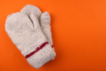 Knitted warm mittens on an orange background