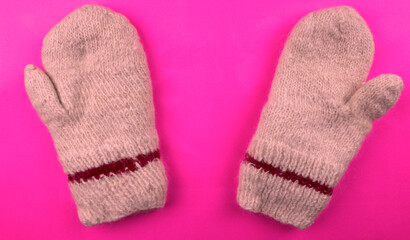 Knitted warm mittens on a pink background