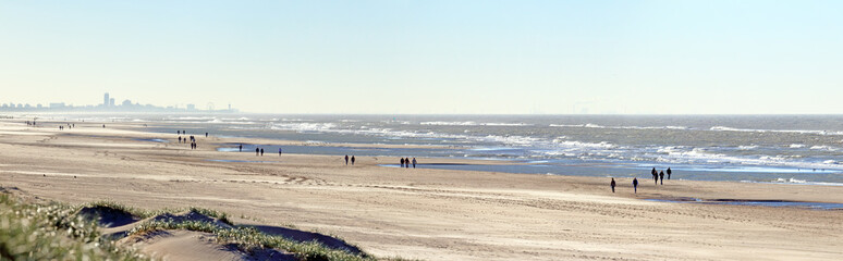 Fototapeta na wymiar Social distance on the beach: people having a walk on a windy day during the Covid lock-down in autumn 2020; Noordwijk, the Netherlands