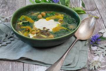 Soupe iranienne aux épinards, pâtes, lentilles et pois-chiches dans une assiette creuse verte