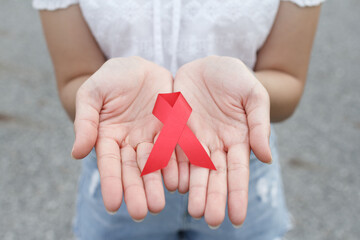 red AIDS awareness ribbon on the hand. World aids day and healthcare and medicine concept