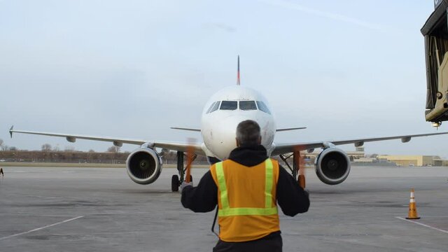 Ground crew member giving a hand signal to the pilot on airplane