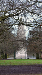 Monument behind branches at the end of a tree alley in winter, Coventry, England