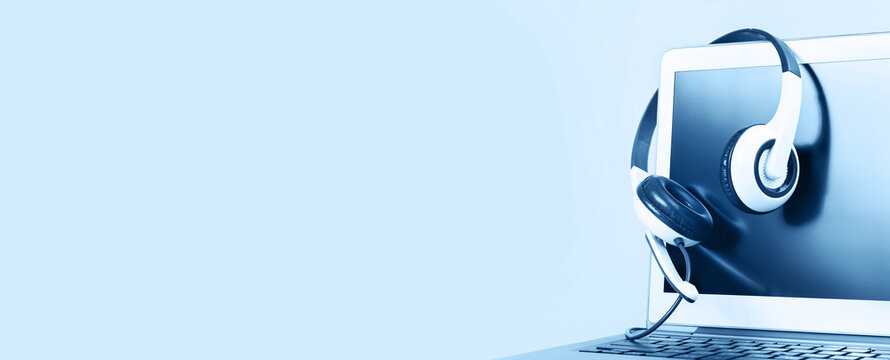 Laptop with blank screen with headphones on white desk blue background and copy space. Distant learning or working from home, online courses or shopping minimal concept. Helpdesk or call center