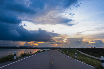 The road on the dam with evening view, blue sky and sun