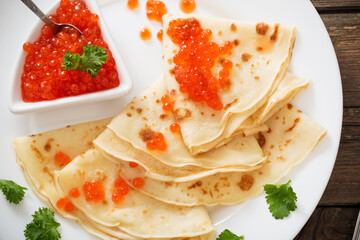 red caviar with pancakes on wooden table