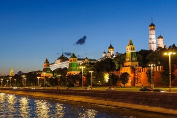 Obraz premium View of the Kremlin embankment, the towers of the Kremlin, the Grand Kremlin Palace, Ivan the Great Bell Tower in the late evening in August. Moscow, Russia