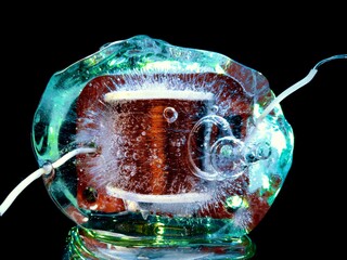 the electric coil of the transformer frozen in ice and illuminated in the dark with green light...