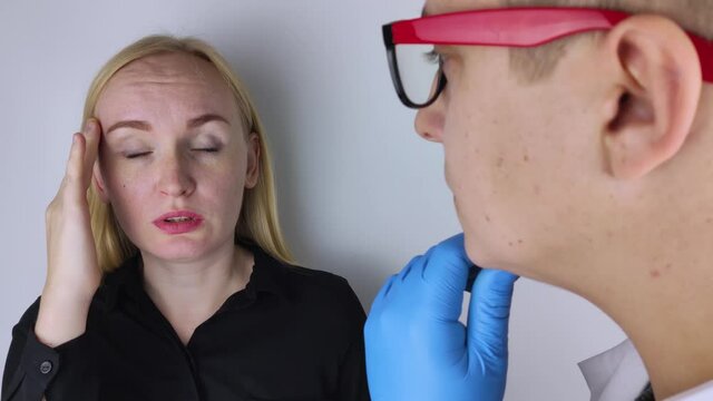 A woman holds his head with his hands. Sensation of headache, migraine and dizziness. Headaches from stress or overwork. On examination by a doctor.