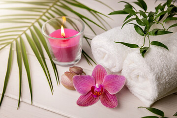 spa towels with candle and pink orchid flower on the white wooden table
