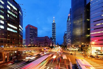 Fototapeta na wymiar Panoramic view of a street corner in Taipei City with busy traffic trails at rush hour ~ Beautiful night scenery of Taipei 101 Tower and World Trade Center in XinYi Commercial Area in Taipei downtown