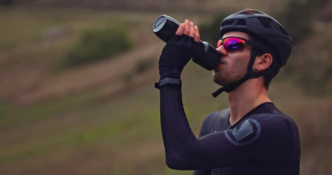 Professional cyclist drinking water from travel bottle