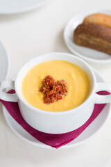 Bowl of yellow pumpkin soup with bacon